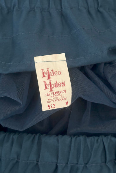 Interior detail view of 1970s vintage dark blue nylon adjustable petticoat by Malco Modes, small, medium, large. Showing the Malco Modes label w/ size M tag.