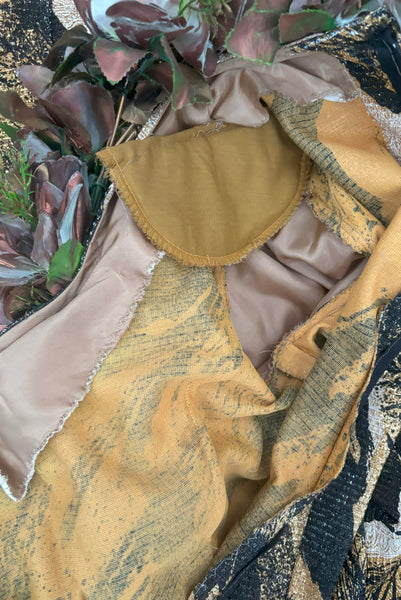 Interior detail view of 1960s vintage metallic black, gold, and white lurex fancy dress costume with copper painted silk flower collar, size medium to large. Showing a bit about the construction, and small shoulder pads.