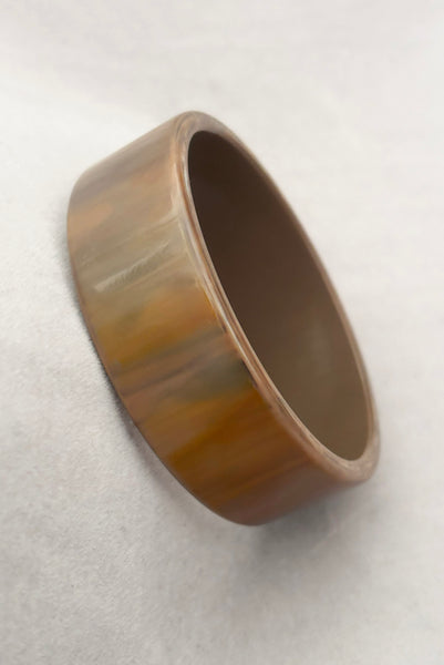 Vertical perspective view of 1950s vintage gray and brown marbled Lucite plastic sliced bangle bracelet.