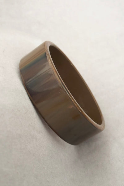 Vertical perspective view of 1950s vintage gray and brown marbled Lucite plastic sliced bangle bracelet.