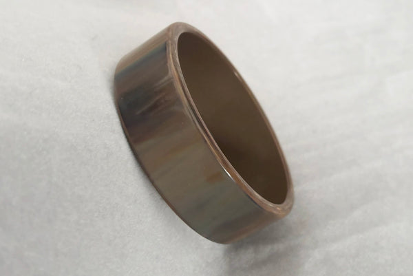 Horizontal perspective view of 1950s vintage gray and brown marbled Lucite plastic sliced bangle bracelet.