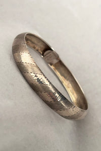 Vertical perspective view of 1970s vintage stripe engraved Italian 925 sterling silver bangle bracelet made in Salerno, Italy.