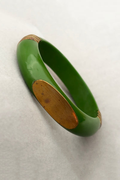Vertical perspective view of 1970s vintage green plastic and brass bangle bracelet, made in India.
