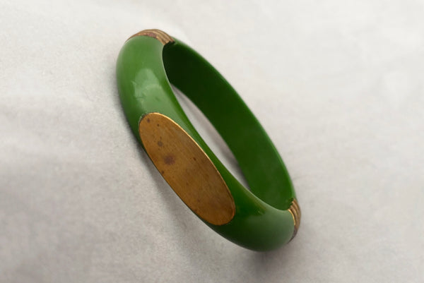 Horizontal perspective view of 1970s vintage green plastic and brass bangle bracelet, made in India.