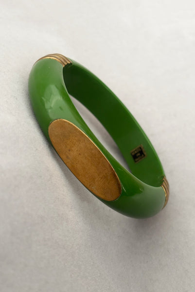 Vertical perspective view of 1970s vintage green plastic and brass bangle bracelet, made in India.