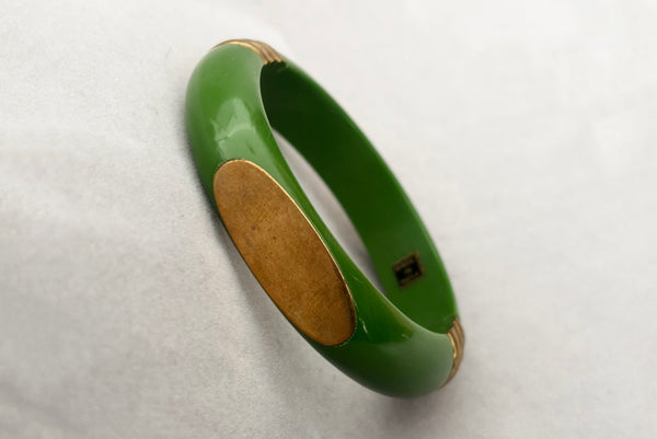 Horizontal perspective view of 1970s vintage green plastic and brass bangle bracelet, made in India.