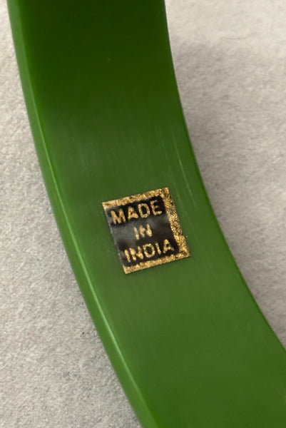 Detail view of 1970s vintage green plastic and brass bangle bracelet, made in India. Showing the "Made in India" sticker