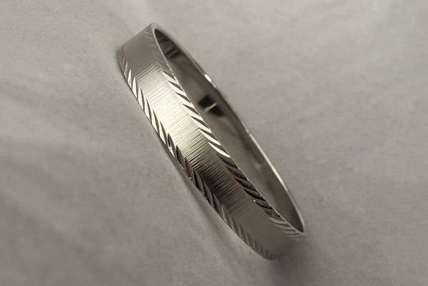 Horizontal perspective view of 1980s vintage petite silver tone chrome engraved bangle bracelet by Monet, size small.