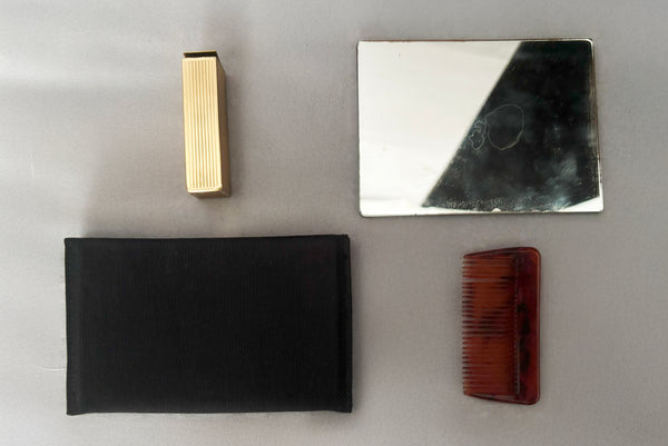 Detail view of 1930s vintage Art Deco black leather gold frame handbag by Evans with coin purse, mirror, comb, and lipstick holder. Showing the mirror with black faille case, pocket comb, and lipstick holder.