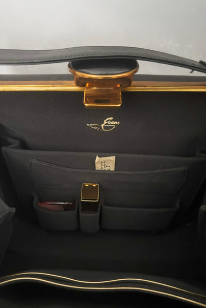 Detail view of 1930s vintage Art Deco black leather gold frame handbag by Evans with coin purse, mirror, comb, and lipstick holder. Showing the interior with black faille lining, storage pockets, and Evans stamp.