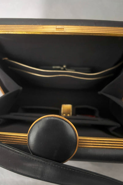 Detail view of 1930s vintage Art Deco black leather gold frame handbag by Evans with coin purse, mirror, comb, and lipstick holder. Showing the interior with black faille lining, storage pockets, and Evans stamp.