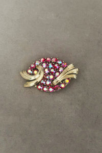 Vertical front view of 1950s vintage oval iridescent fuchsia pink rhinestone and champagne metal brooch, by Lisner.