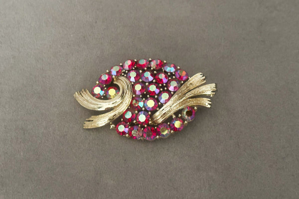 Horizontal front view of 1950s vintage oval iridescent fuchsia pink rhinestone and champagne metal brooch, by Lisner.