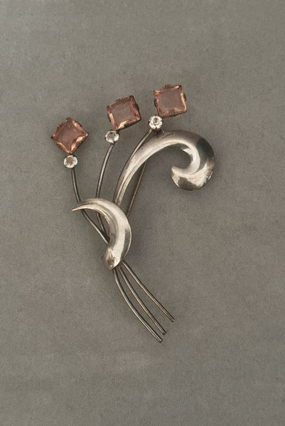 Vertical front view of 1950s vintage 925 sterling silver, square princess cut pink rhinestone, and round clear rhinestone modernist floral botanical brooch.