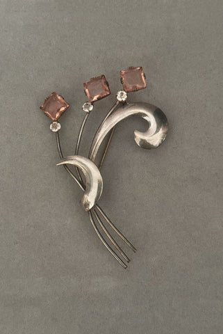 Vertical front view of 1950s vintage 925 sterling silver, square princess cut pink rhinestone, and round clear rhinestone modernist floral botanical brooch.