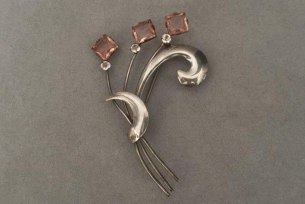 Horizontal front view of 1950s vintage 925 sterling silver, square princess cut pink rhinestone, and round clear rhinestone modernist floral botanical brooch.