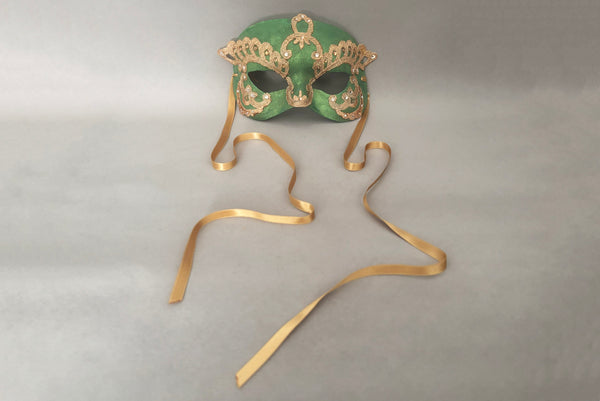Horizontal front view of 1990s gold Lurex lace, gold Swarovski crystal, and metallic green painted half mask with gold satin ribbon ties. Showing the gold satin ribbon ties.