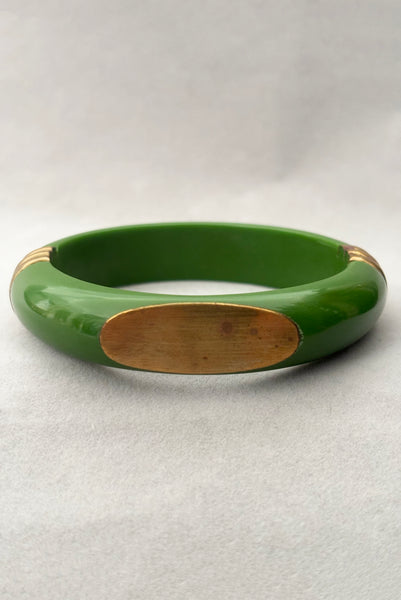 Vertical front view of 1970s vintage green plastic and brass bangle bracelet, made in India. Showing some spots on the brass plate.
