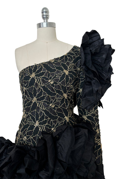 Bodice front view of 1980s vintage black & gold floral embroidered one shoulder ruffled silk evening dress, size extra small to small. Showing the gold floral embroidered ruffled one shoulder bodice with dropped waist.