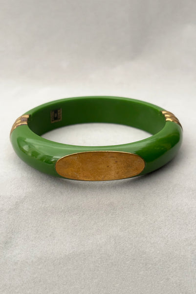 Vertical front view of 1970s vintage green plastic and brass bangle bracelet, made in India.