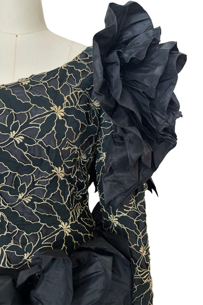 Detail view of 1980s vintage black & gold floral embroidered one shoulder ruffled silk evening dress, size extra small to small. Showing the gold floral embroidered ruffled one shoulder bodice with dropped waist.
