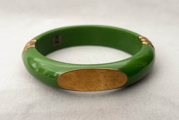 Horizontal front view of 1970s vintage green plastic and brass bangle bracelet, made in India.