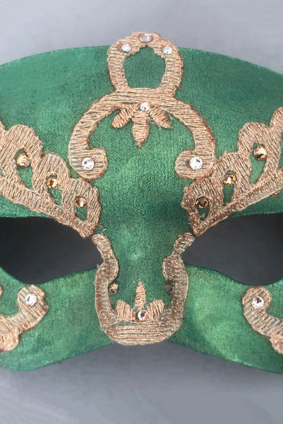 Vertical detail view of 1990s gold Lurex lace, gold Swarovski crystal, and metallic green painted half mask with gold satin ribbon ties. Showing the light gold and gold Swarovski crystals.