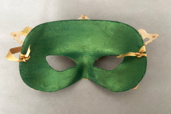 Horizontal back view of 1990s gold Lurex lace, gold Swarovski crystal, and metallic green painted half mask with gold satin ribbon ties. Showing the inside of the mask.