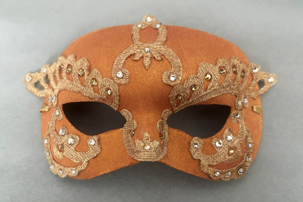 Horizontal flat view of 1990s gold Lurex lace, gold Swarovski crystal, and metallic pink rose gold painted half mask with gold satin ribbon ties.