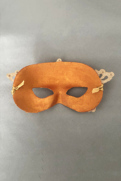 Vertical back view of 1990s gold Lurex lace, gold Swarovski crystal, and metallic pink rose gold painted half mask with gold satin ribbon ties. Showing the inside of the mask.