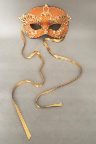 Vertical front view of 1990s gold Lurex lace, gold Swarovski crystal, and metallic pink rose gold painted half mask with gold satin ribbon ties. Showing the gold satin ribbon ties.