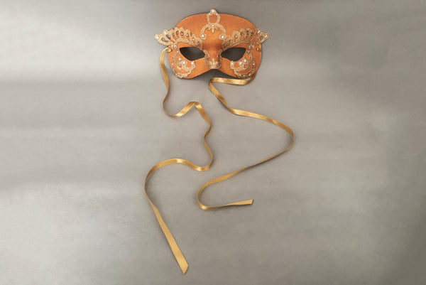 Horizontal front view of 1990s gold Lurex lace, gold Swarovski crystal, and metallic pink rose gold painted half mask with gold satin ribbon ties. Showing the gold satin ribbon ties.
