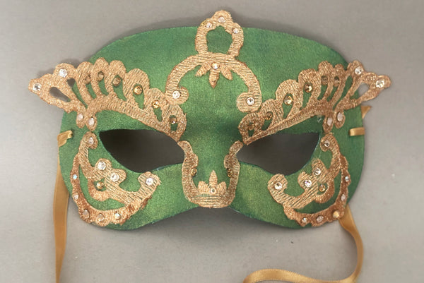 Horizontal detail view of 1990s gold Lurex lace, gold Swarovski crystal, and metallic green painted half mask with gold satin ribbon ties. Showing the light gold and gold Swarovski crystals.