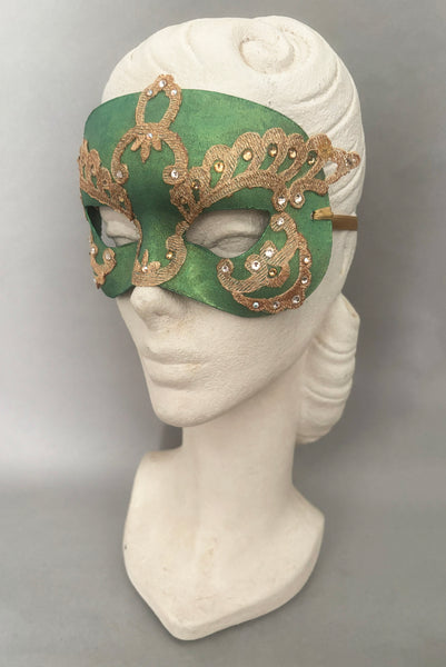 Vertical 3/4 view of 1990s gold Lurex lace, gold Swarovski crystal, and metallic green painted half mask with gold satin ribbon ties. Showing the mask on a mannequin head.