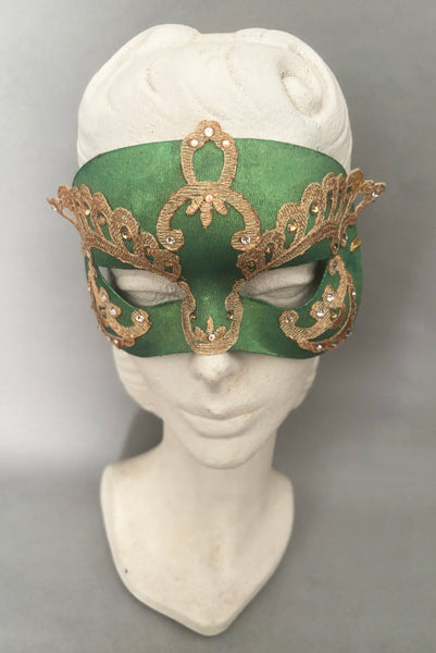 Vertical front view of 1990s gold Lurex lace, gold Swarovski crystal, and metallic green painted half mask with gold satin ribbon ties. Showing the mask on a mannequin head.