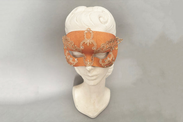 Horizontal front view of 1990s gold Lurex lace, gold Swarovski crystal, and metallic pink rose gold painted half mask with gold satin ribbon ties. Showing the mask on a mannequin head.