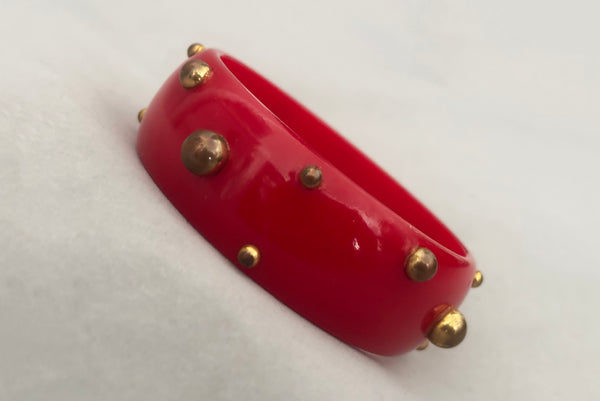 Horizontal perspective view of 1940s vintage brass studded rich cherry red Bakelite statement bangle bracelet.