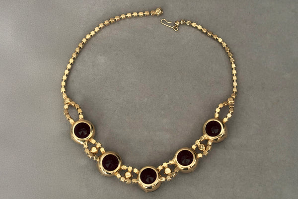 Horizontal flat lay back view of 1950s vintage pink and large Purple rhinestone adjustable gold tone necklace.