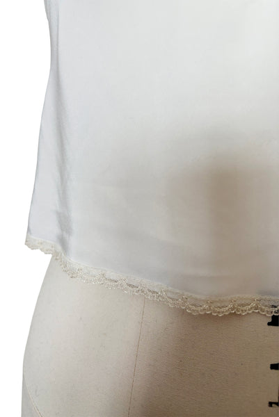 Detail view of 1970s vintage white polyester challis and floral lace faux pearl embellished lingerie camisole top by Christian Dior, size small to medium.  Showing the scalloped lace hem.