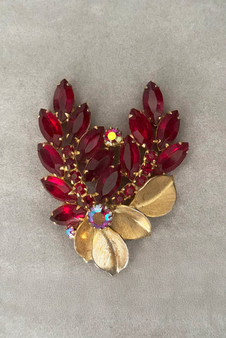 Vertical front view of 1950s vintage iridescent crimson red rhinestone and gold tone floral brooch.