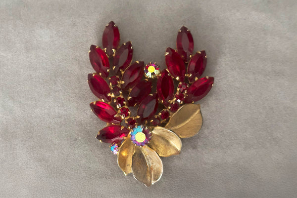 Horizontal front view of 1950s vintage iridescent crimson red rhinestone and gold tone floral brooch.