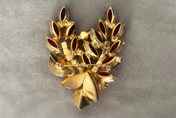 Horizontal back view of 1950s vintage iridescent crimson red rhinestone and gold tone floral brooch.