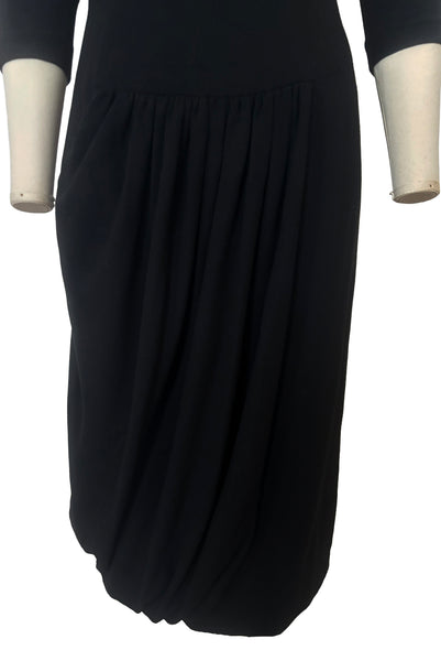 Skirt front view of 1940s vintage black wool crew neck, 3/4 sleeve, drop waist dress with asymmetrical gathered front draped wrap skirt, size extra small to small. Showing the details of the skirt.