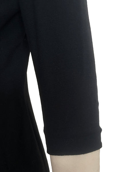 Detail view of 1940s vintage black wool crew neck, 3/4 sleeve, drop waist dress with asymmetrical gathered front draped wrap skirt, size extra small to small. Showing a small snag in the black wool on the sleeve.