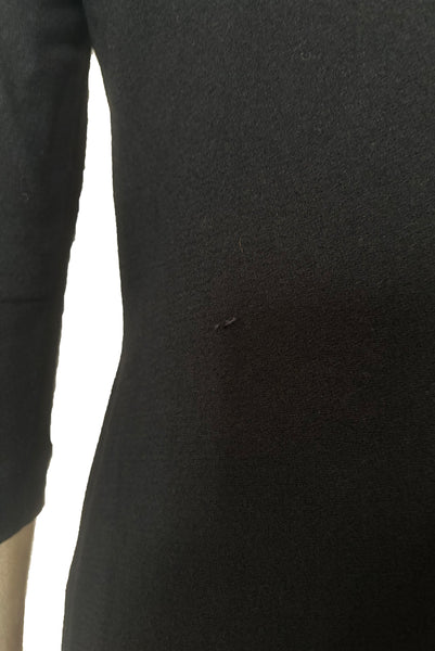 Detail view of 1940s vintage black wool crew neck, 3/4 sleeve, drop waist dress with asymmetrical gathered front draped wrap skirt, size extra small to small. Showing a small snag in the black wool on the dress back.