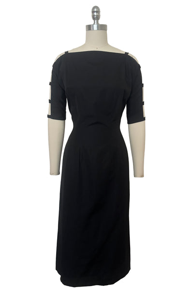 Front view of 1950s vintage black boat neck, raglan open sleeve wiggle dress, size small to medium.
