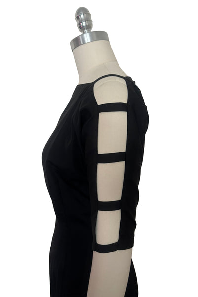 Bodice side view of 1950s vintage black boat neck, raglan open sleeve wiggle dress, size small to medium. Showing the open ladder pattern sleeves.