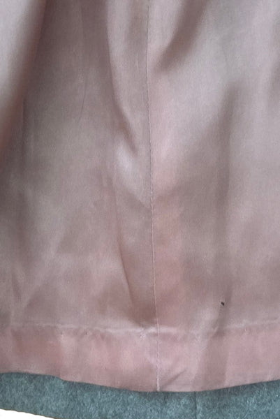 Interior detail view of 1960s vintage heavy gray and rust tie waist wool coat by Carol Cohen for Braefair, size medium to large. Showing minor damage to the pink satin lining near the hem.
