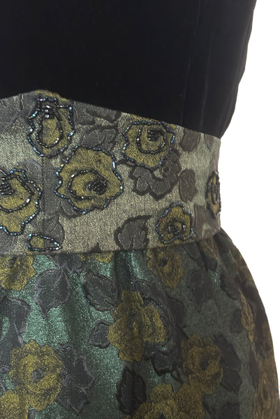 Detail view of 1950s vintage black velvet crew neck, sleeveless, green floral brocade pencil skirt cocktail dress, with beaded belt, size medium to large. Showing the pointed matching belt embellished with iridescent glass seed beads.