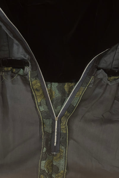 Detail view of 1950s vintage black velvet crew neck, sleeveless, green floral brocade pencil skirt cocktail dress, with beaded belt, size medium to large. Showing the black voile underlining and metal zipper.